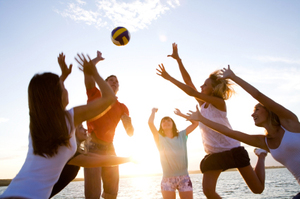 group of young people playing volleyball on the beach