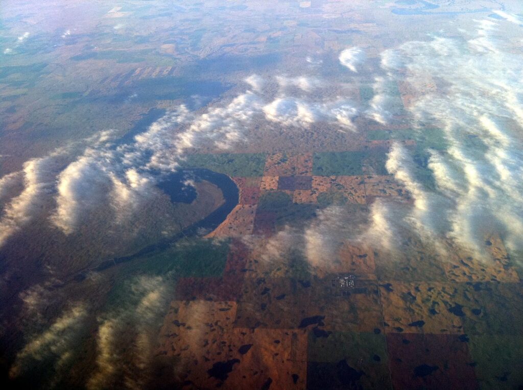 Farmlands and cleff-shaped lake, over Manitoba